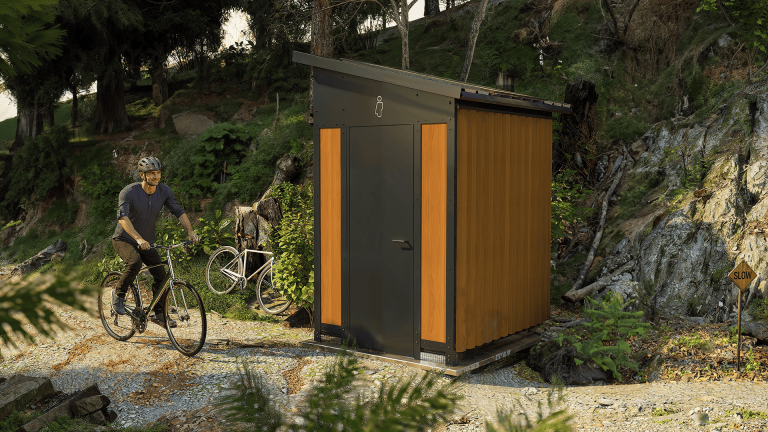 Un monsieur en vélo qui passe devant la toilette écologique NIX-02